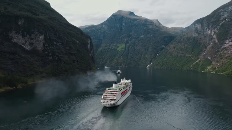 A ship sailing through a narrow Norwegian fjord surrounded by steep cliffs.